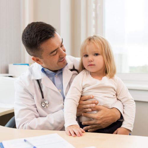 medicine, healthcare, pediatry and people concept - happy doctor or pediatrician holding little girl patient on medical exam at clinic